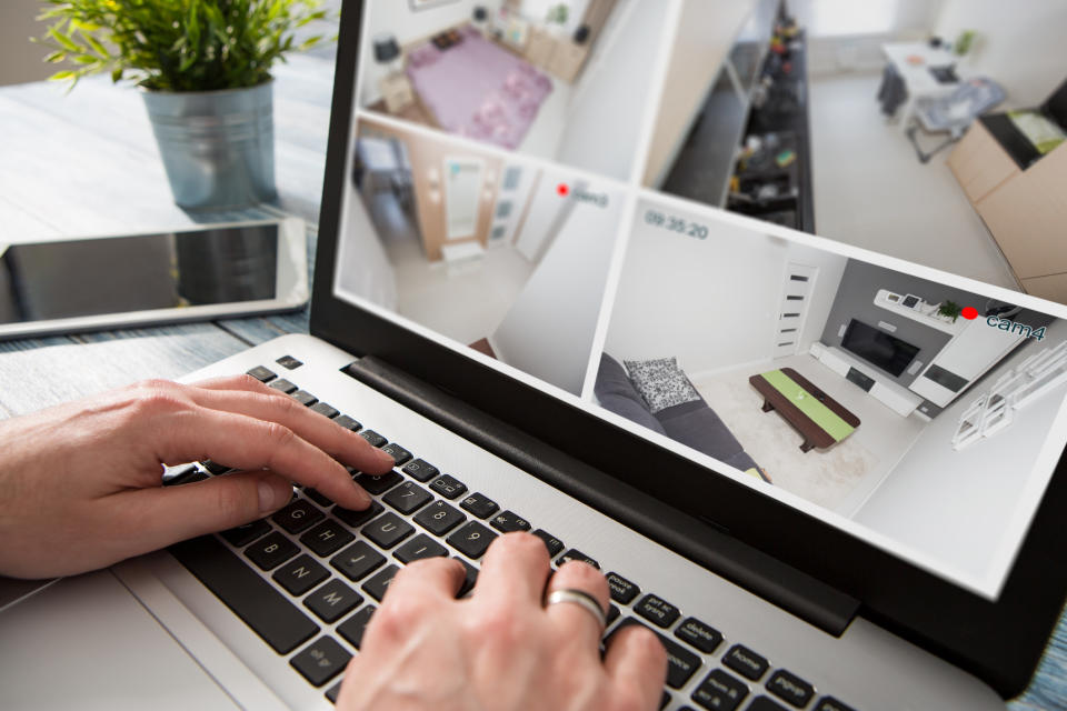 Person monitoring home security cameras on a laptop