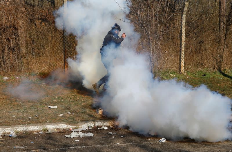 A migrant runs through a cloud of tear gas during clashes with Greek police, at the Turkey's Pazarkule border crossing with Greece's Kastanies, in Edirne