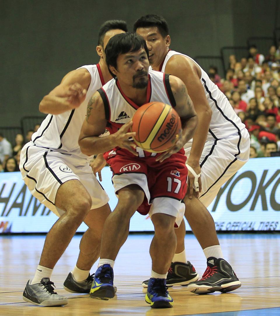 Manny Pacquiao, a playing coach of KIA-Sorento, is guarded by players of Blackwater-Elite during the first quarter of the 40th Season of the Philippine Basketball Association (PBA) games in Bocaue town, Bulacan province, north of Manila October 19, 2014. Pacquiao, a congressman and a world renowned boxing champion, ventured into the PBA as a playing coach on Sunday. Manny Pacquiao is scheduled for a title bout against Chris Algieri of the U.S. in Macau on November 22. REUTERS/Romeo Ranoco (PHILIPPINES - Tags: SPORT BOXING POLITICS BASKETBALL)