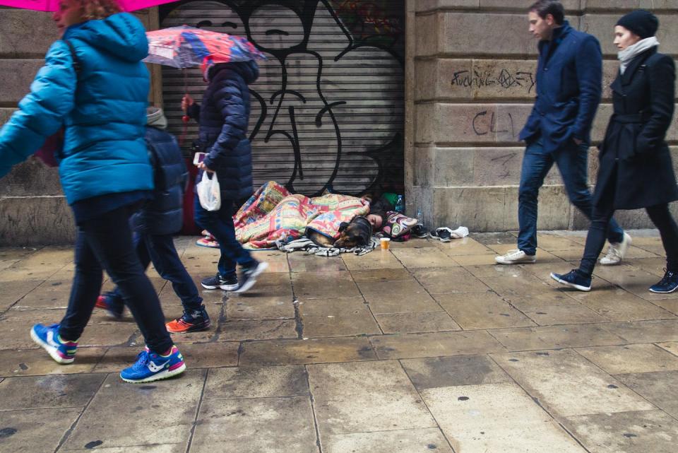 Una persona y un perro duermen en una calle de Barcelona un día lluvioso. <a href="https://www.shutterstock.com/es/image-photo/barcelona-spain-february-4-2018-young-1087615184" rel="nofollow noopener" target="_blank" data-ylk="slk:Shutterstock / Bogdan Khmelnytskyi;elm:context_link;itc:0;sec:content-canvas" class="link ">Shutterstock / Bogdan Khmelnytskyi</a>