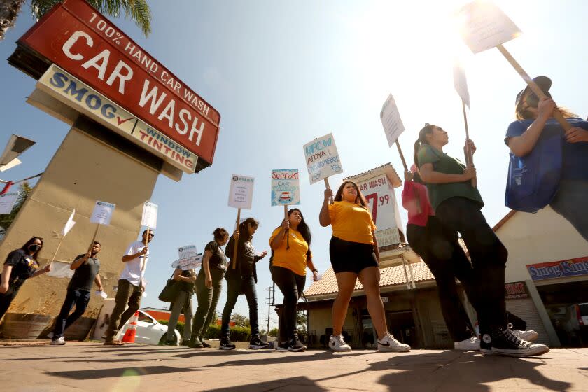 INGLEWOOD, CA - JULY 11, 2023 - UCLA students Abril Olalde, 21, center, in shorts, and Karen Magana, 26, center, UCLA students Karen Magana, 26, left, and Abril Olalde, 21, with UFCW 770, join others who picket in front of the Shine N Brite Car Wash in Inglewood on July 11, 2023. Magana and Olalde are interning with UFCW 770 as part of UC's Labor Summer. Shine N Brite Car Wash came under fire in November when state officials penalized the carwash operator for paying workers below minimum wage and denying them overtime and rest breaks. According to a fellow with UC Labor Summer, the owner has neglected to increase pay to the workers and was delivered a letter with their health and safety concerns. $13 million funding was recently given to open six new UC labor centers in what is touted as the largest expansion of academic labor centers in history, and the first-ever UC Labor Summer, where undergrad/grad students (labor fellows) are paired with host organizations to learn more about labor rights/organizing. (Genaro Molina/Los Angeles Times)