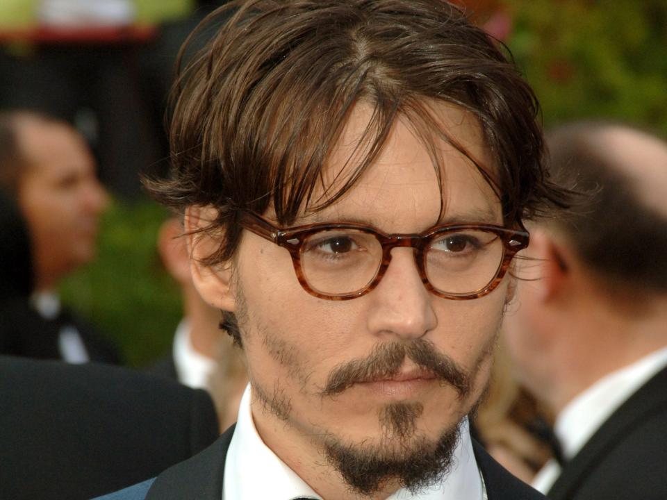 johnny depp in 2005 at the academy awards, wearing a blue blazer with a white collar, a bow tie, and tortoiseshell glasses