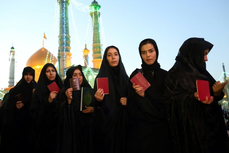 Iranian women hold their identity cards as they queue to vote in the May 19, 2017 presidential election at the Massoumeh shrine in the Shiite Muslim holy city of Qom