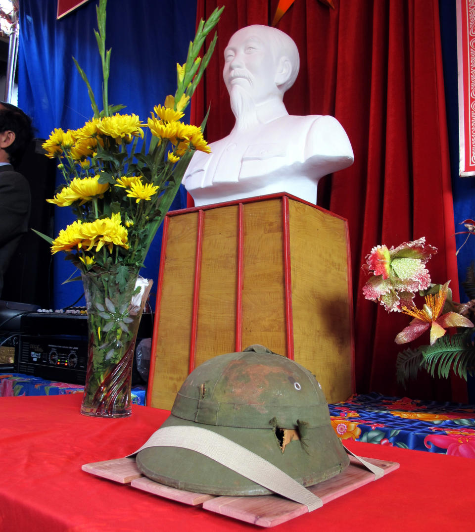 A dented helmet belonging to Bui Duc Hung, a slain North Vietnamese soldier who died during the Vietnam War, is displayed in front of a bust of late Vietnamese revolutionary leader Ho Chi Minh in Huong Non village, northern Phu Tho province, Vietnam on Tuesday, Jan. 14, 2014. The helmet, which had been kept as a war souvenir by an American veteran for 46 years, was returned to the extended family of Bui Duc Hung. (AP Photo/Tran Van Minh.)