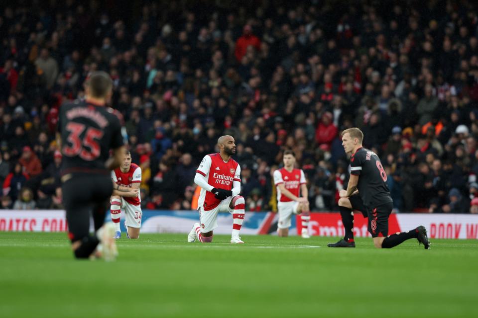Arsenal's Alexandre Lacazette (center) and other players take a knee before the start of the English Premier League soccer match between Arsenal and Southampton at Emirates stadium in London in a December 2021 match.