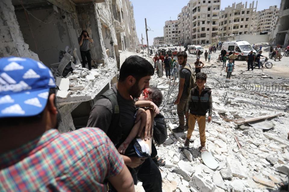 A man carries a wounded child after a car bombing in Syria in May (AFP/Getty/Omar Haj Kadour)