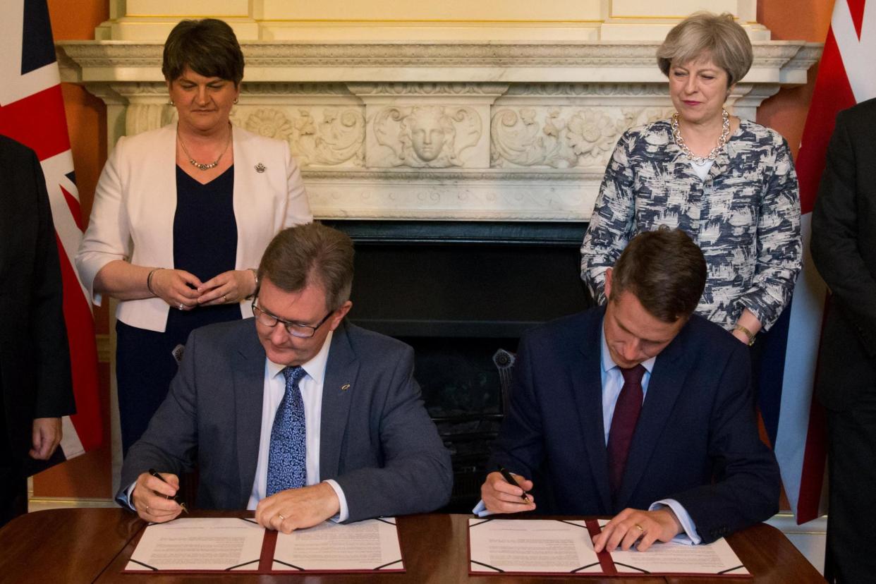 DUP leader Arlene Foster and PM Theresa May watch as DUP MP Jeffrey Donaldson and Chief Whip Gavin Williamson sign paperwork: REUTERS