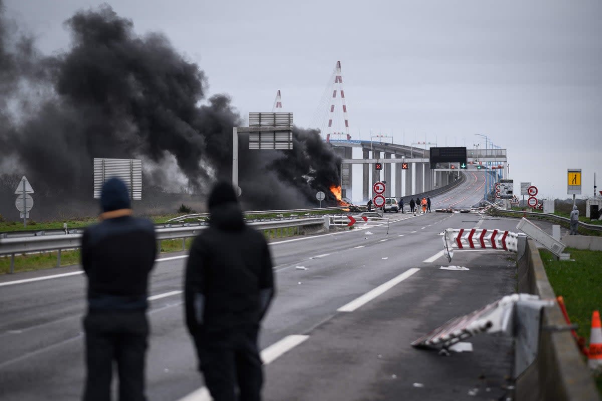 Protestors look on next to a damaged and burning road sign gantry at the entrance of the "Pont de Saint-Nazaire" (Saint-Nazaire bridge), the longest bridge in France (AFP/Getty)