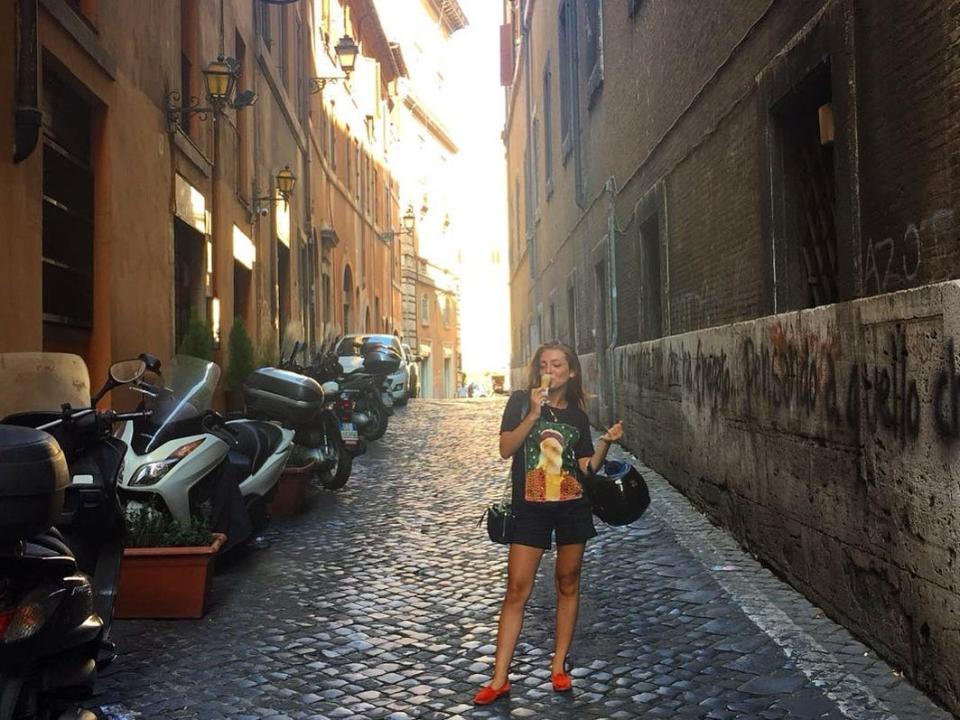 woman in an alleyway eating an icrecream in rome italy