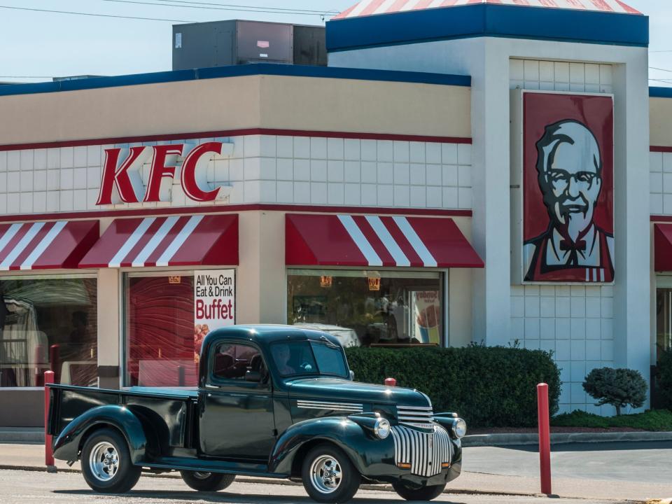 A pick up truck is parked in front of a KFC store.