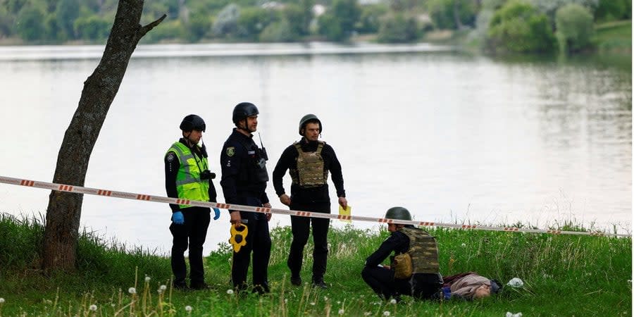 Police officers examine the body of a person killed as a result of Russian missile strikes on a recreation center in Cherkaska Lozova