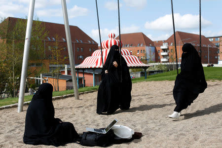 Zaynab (C) who lives in Mjolnerparken, a housing estate that features on the Danish government's "Ghetto List", sits with her friends Amira and Sabrina in Superkilen, a recently designed urban renewal park that runs beside Mjolnerparken, in Copenhagen, Denmark, May 3, 2018. REUTERS/Andrew Kelly