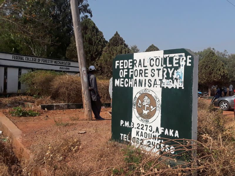 Man rests on a pole beside the signage of the Federal College of Forestry Mechanization where gunmen abducted students, in Kaduna