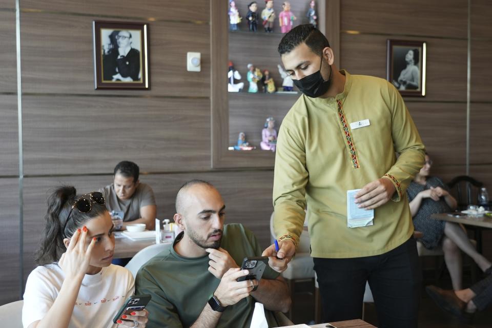 Ali el-Sayyed Mohammed toma un pedido a clientes en el restaurante Hadoota Masreya en Dubái, Emiratos Árabes Unidos, el 5 de septiembre de 2022. Mohammed se marchó de su localidad natal de Beheira, en el Delta del Nilo, para instalarse en Dubái con la esperanza de ganarse la vida. Mohammed, de 26 años, dijo que mantiene a su madre y sus hermanas en casa. (AP Foto/Malak Harb)