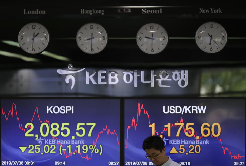 A currency trader walks by the screens showing the Korea Composite Stock Price Index (KOSPI), left, and the foreign exchange rate between U.S. dollar and South Korean won at the foreign exchange dealing room in Seoul, South Korea, Monday, July 8, 2019. Asian stocks tumbled Monday after relatively strong U.S. employment data tempered hopes the Federal Reserve might cut interest rates. (AP Photo/Lee Jin-man)