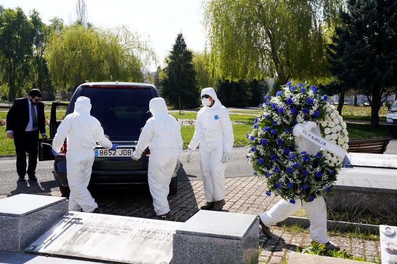 Municipal workers wearing protective gear carry a wreath for a victim of coronavirus disease (COVID-19) at El Salvador cemetery in Vitoria