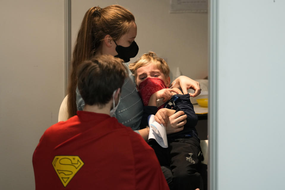 FILE- Volunteer dressed in a costume talks to a young boy who is about to receive the COVID-19 vaccine at vaccination center in Prague, Czech Republic, Saturday, Jan. 8, 2022. The number of COVID-19 patients in the Czech Republic has begun to grow amid a record surge of infections driven by the highly contagious omicron coronavirus variant. According to the figures released by Health Ministry on Tuesday Jan. 25, 2022. The number of hospitalized jumped to 1,695 on Monday and was on the rise for the second straight day, up from 1,537 the previous day. (AP Photo/Petr David Josek, File)