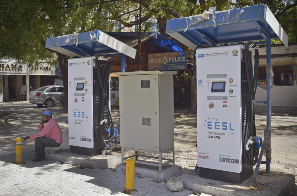 An attendant of a public charging station for electric vehicles sits idle in New Delhi, India, Thursday, April 1, 2021. India has ambitions to expand use of electric vehicles to wean itself from polluting fossil fuels, but EVs are still a rarity on its congested highways. A lack of charging stations and poor quality batteries are discouraging drivers from switching over. (AP Photo/Neha Mehrotra)