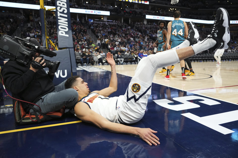 Denver Nuggets forward Michael Porter Jr. falls into a cameraman while playing against the Detroit Pistons during the third quarter of an NBA basketball game, Tuesday, Nov. 22, 2022, in Denver. (AP Photo/Jack Dempsey)