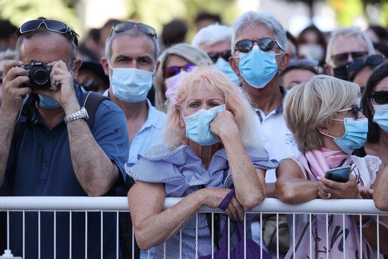 Onlookers wearing masks for protection against the COVID-19 pandameic watch guests arriving for the screening of the film "Benedetta" at the 74th edition of the Cannes Film Festival in Cannes