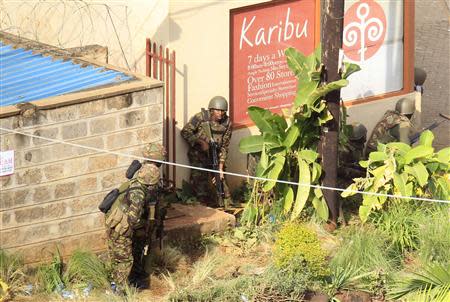 Kenya Defence Forces soldiers take cover behind walls near the Westgate shopping centre after an exchange of gunfire inside the mall in Nairobi September 23, 2013. REUTERS/Noor Khamis