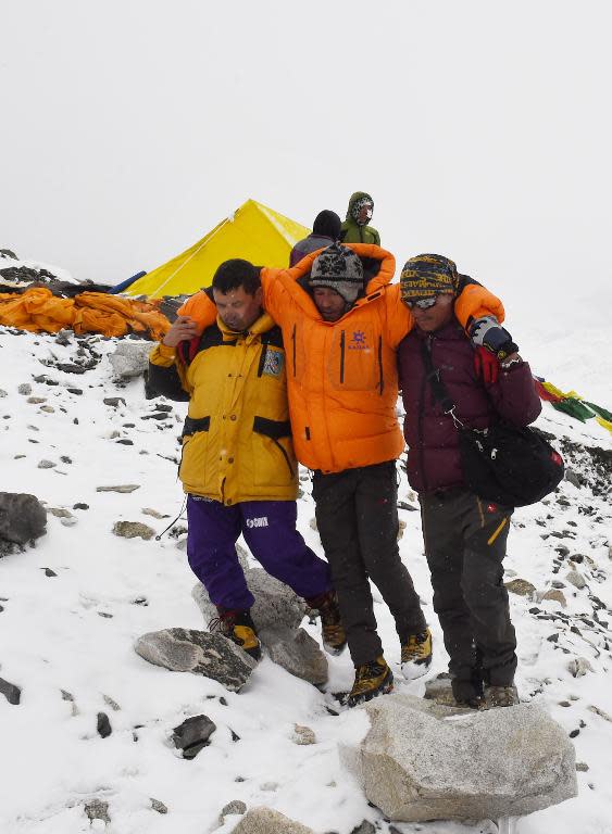 In this photograph taken on April 25, 2015, rescuers assist an injured person after an earthquake triggered by an avalanche flattened parts of Everest Base Camp