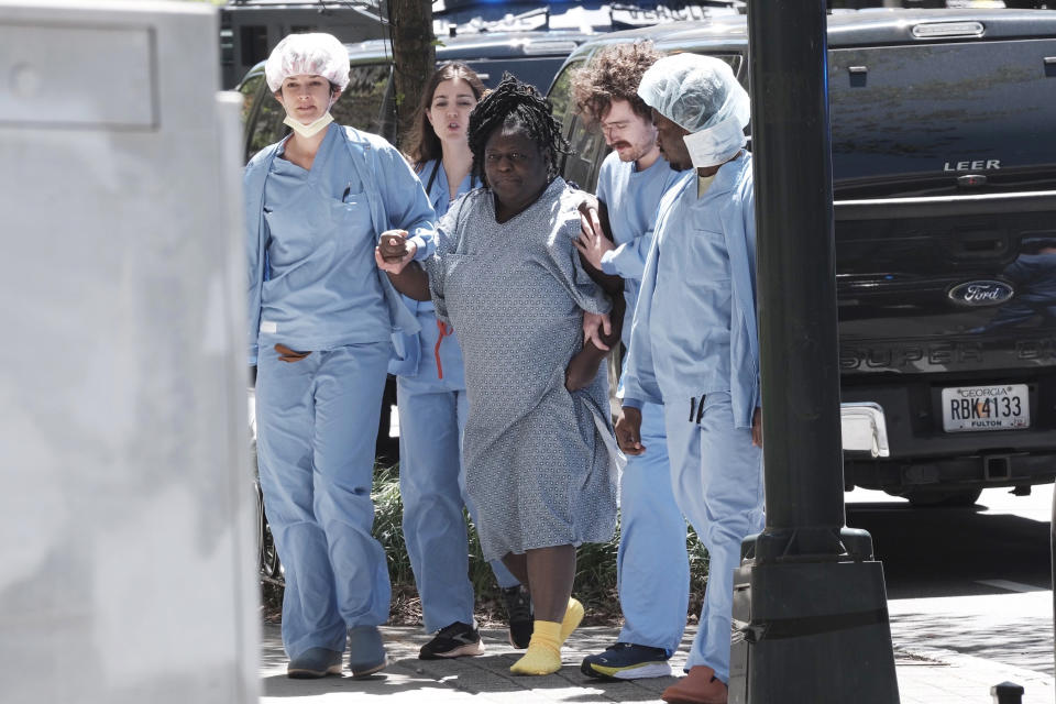 A medical patient is helped away from the scene of an active shooter on Wednesday, May 3, 2023 in Atlanta. Atlanta police said there had been no additional shots fired since the initial shooting unfolded inside a building in a commercial area with many office towers and high-rise apartments. (AP Photo/Ben Gray)