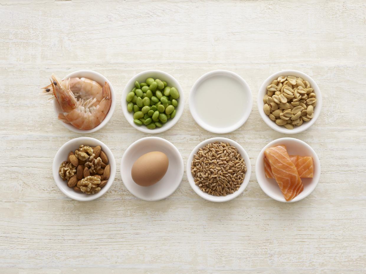 Small bowls of food including shrimp, edamame, an egg, nuts, milk and salmon