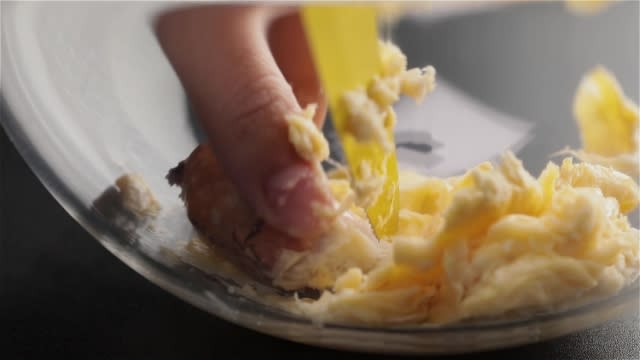 Scrapping durian flesh from durian seed with a small yellow knife