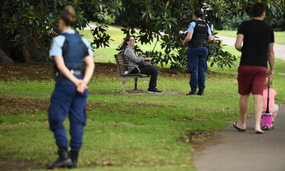 Police officers ask people sitting in parks to go home