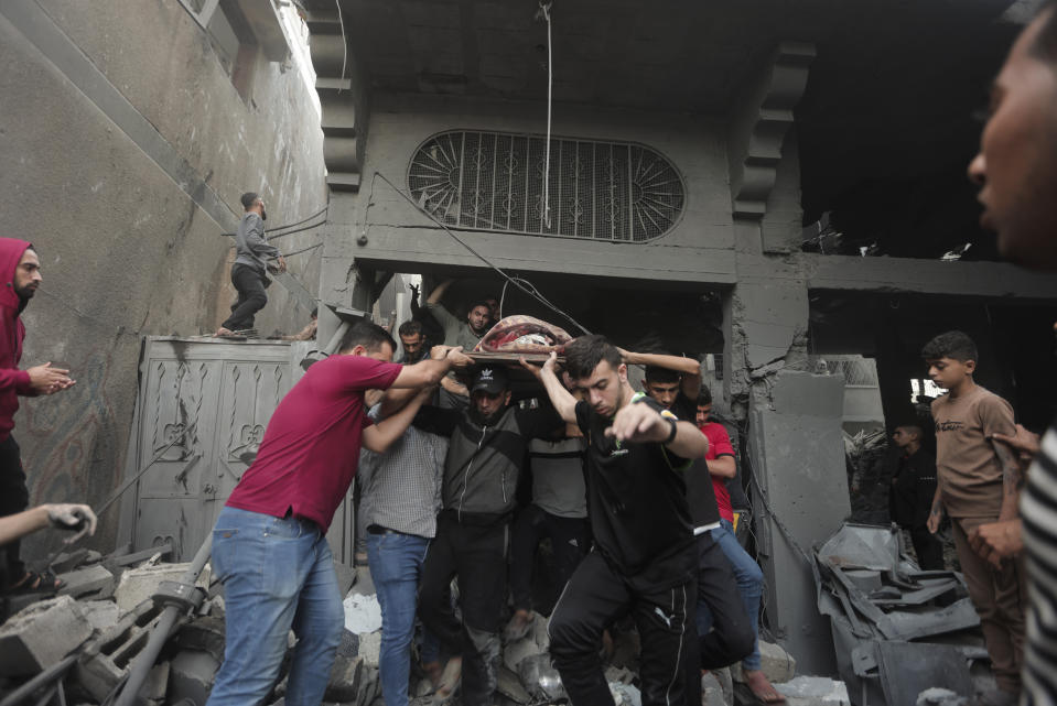 Palestinians evacuate an injured woman that was found under the rubble of a destroyed house following an Israeli airstrike in Khan Younis refugee camp, southern Gaza Strip, Saturday, Nov. 18, 2023. (AP Photo/Mohammed Dahman)