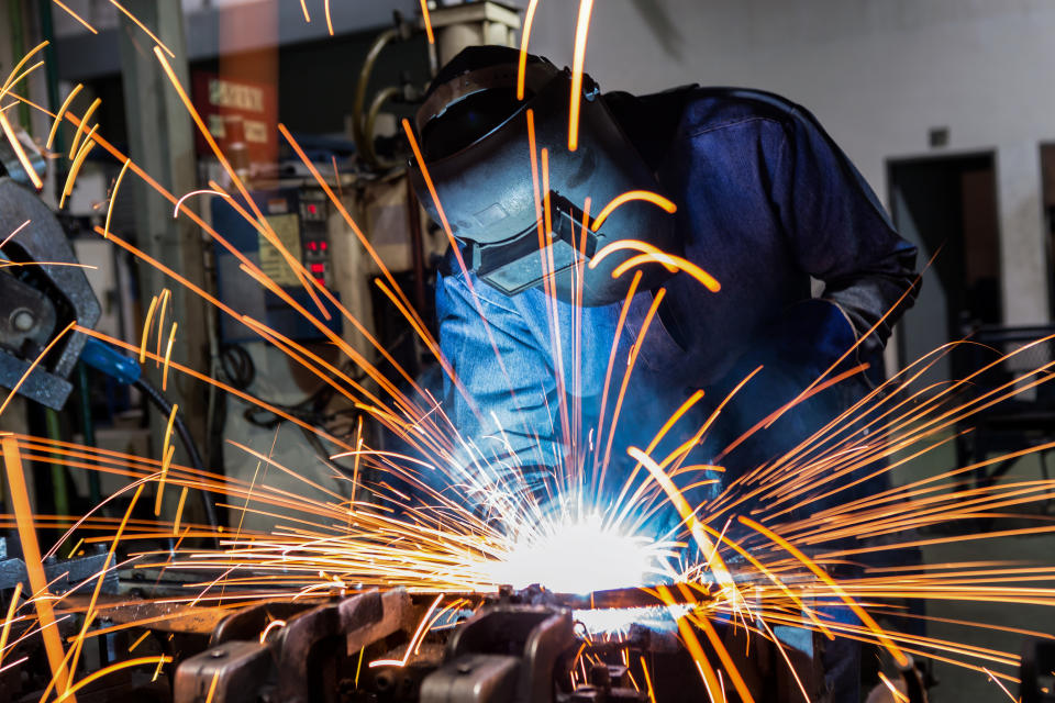 A man operating welding equipment, with sparks flying everywhere..