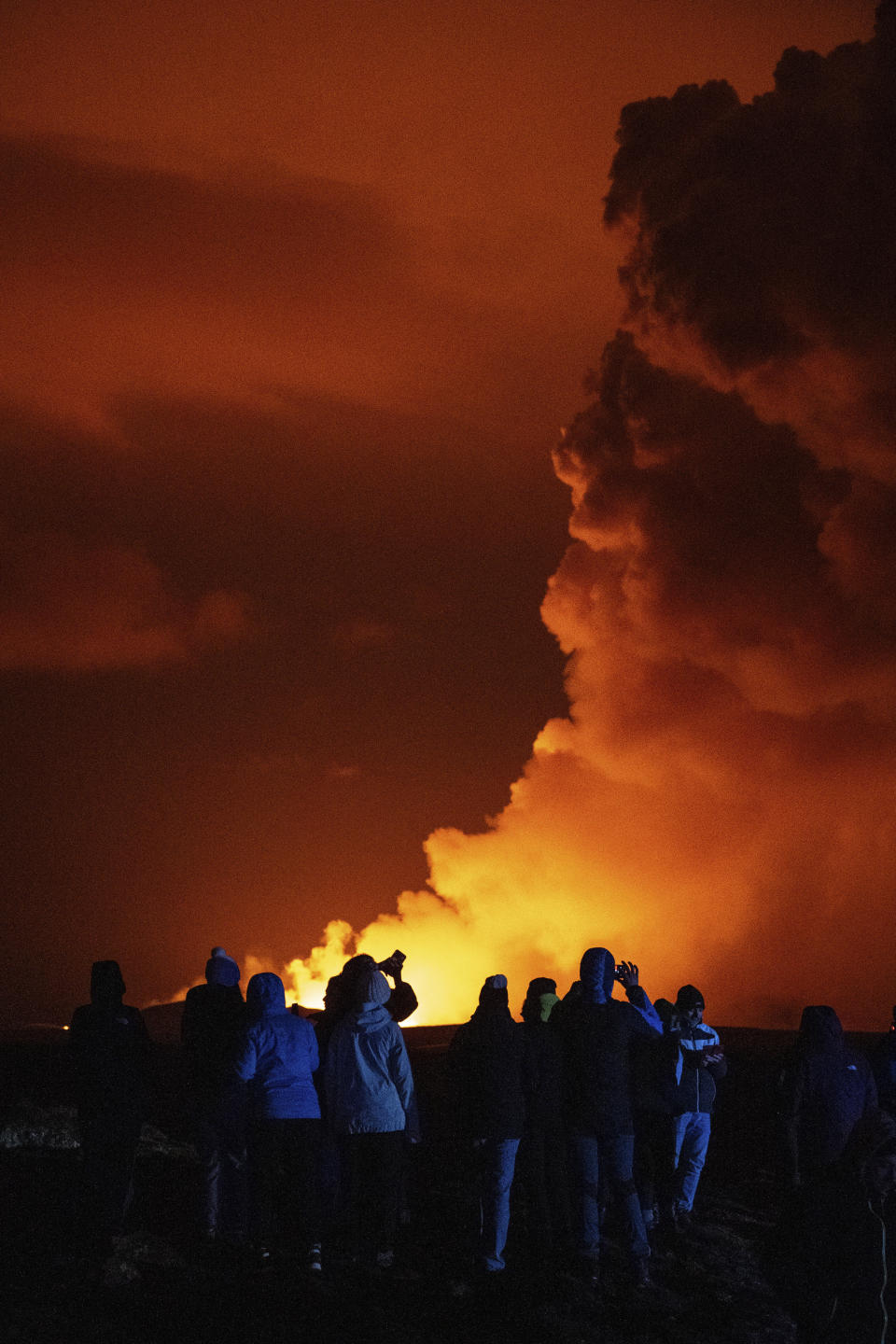 Spectators watch plumes of smoke from volcanic activity between Hagafell and Stóri-Skógfell, Iceland, on Saturday, March 16, 2024. (AP Photo/Marco di Marco)