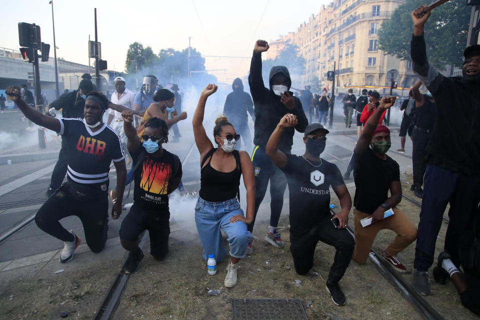 Protesters react during a demonstration Tuesday, June 2, 2020 in Paris. Paris riot officers fired tear gas as scattered protesters threw projectiles and set fires at an unauthorized demonstration against police violence and racial injustice. Several thousand people rallied peacefully for two hours around the main Paris courthouse in homage to George Floyd and to Adama Traore, a French black man who died in police custody. (AP Photo/Michel Euler)