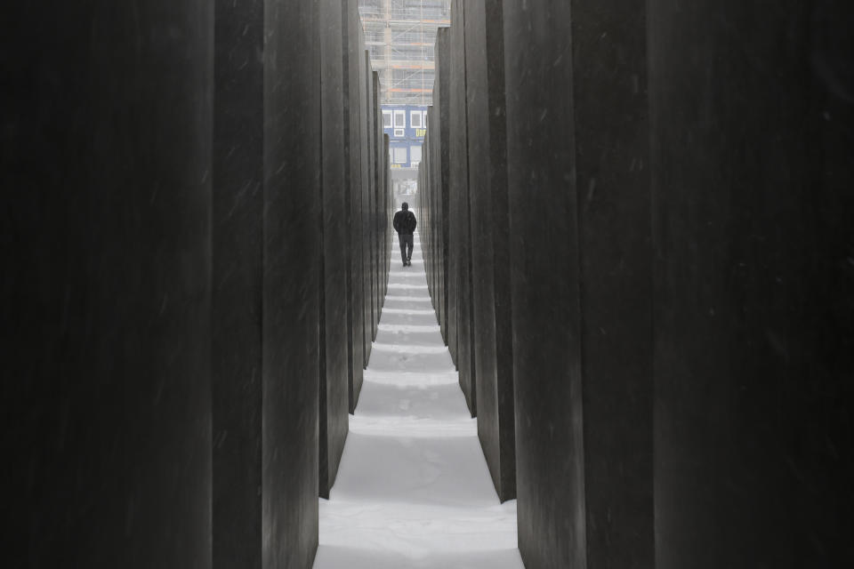 FILE - In this Feb.7, 2021 file photo a man visits the Holocaust Memorial during snowfall in central Berlin, Germany. Germany has committed millions of dollars in extra funding to survivors of the Nazi Holocaust to help ensure that all of them are able to get vaccinated against the coronavirus, the organization that handles claims on behalf of Jewish victims said Wednesday.(AP Photo/Markus Schreiber)