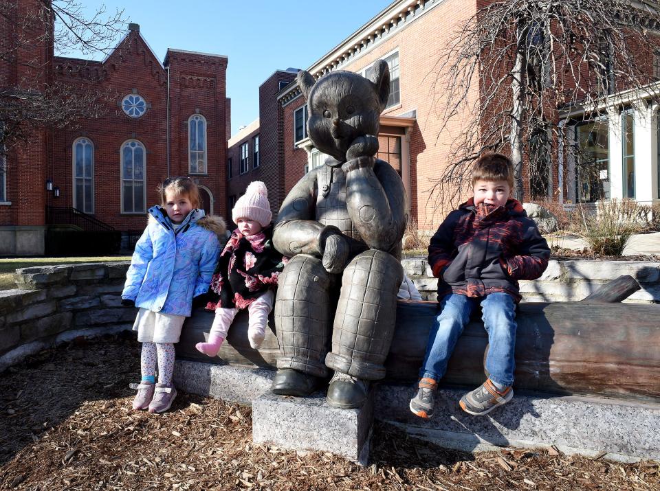 Josie Gaynier, 3, left, with 17-month-old Lilly Gaynier and John Gaynier, 4, spend time at the Little Brown Bear statue outside the Dorsch Memorial Library in downtown Monroe.