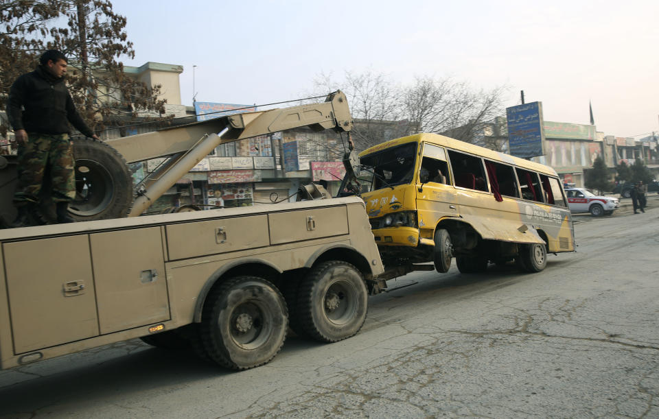 An Afghan National Army (ANA) truck removes a destroyed ANA minibus from the site of a suicide attack in Kabul, Afghanistan, Sunday, Jan. 26, 2014. An Afghan official said a suicide bomber attacked a military bus in Kabul, killing at least four people. (AP Photo/Massoud Hossaini)