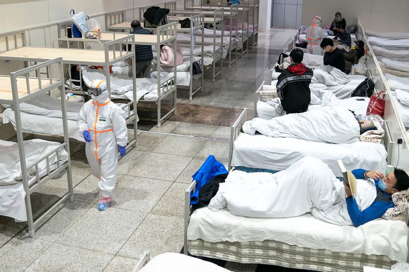 Medical workers in protective suits attend to patients at the Wuhan International Conference and Exhibition Center