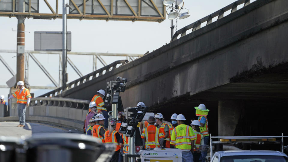 Workers stage at the site of a weekend fire under a burned overpass along interstate 10, Monday, Nov. 13, 2023, in Los Angeles. Los Angeles drivers are being tested in their first commute since a weekend fire that closed a major elevated interstate near downtown. (AP Photo/Ryan Sun)