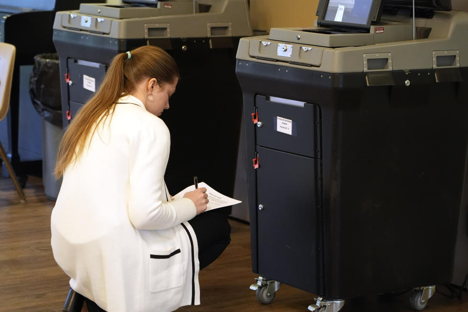 A Mississippi Republican Party poll worker documents the security on the electronic ballot boxes at this north Jackson, Miss., election precinct during Mississippi's party primaries, Tuesday, March 12, 2024. (AP Photo/Rogelio V. Solis)