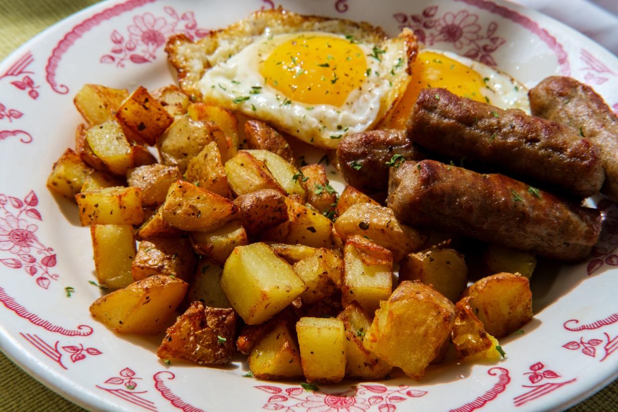 Fried sunny side up American egg breakfast with sausage and home fries