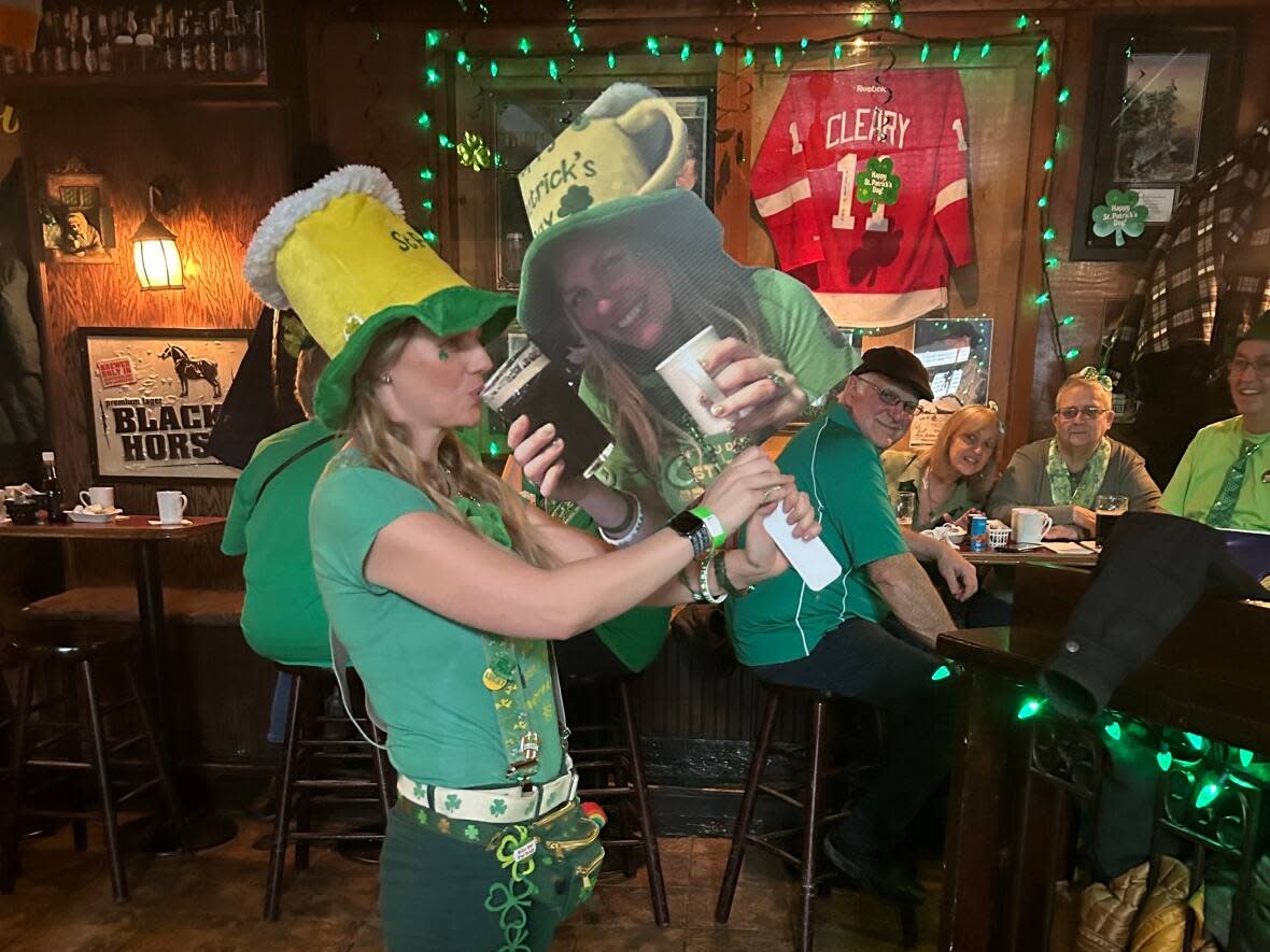 Nikki Davis of St. John's wasn't sure she'd be able to make St. Patrick's Day festivities this year after being admitted to hospital with pancreatitis, which prompted her friends to make this cardboard cutout of her to drink with. Now out of hospital, she has a new drinking buddy. (Ife Alaba/CBC - image credit)