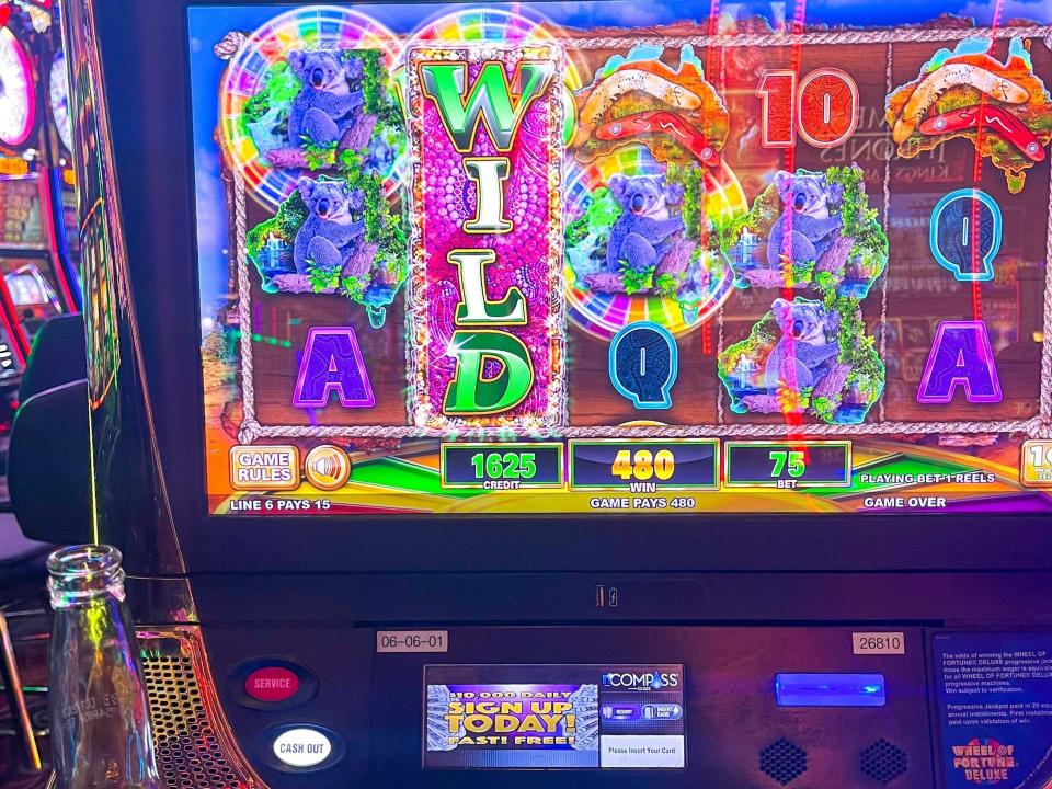 A Wheel of Fortune slot machine with a colorful screen and a Corona beer set next to one of the buttons