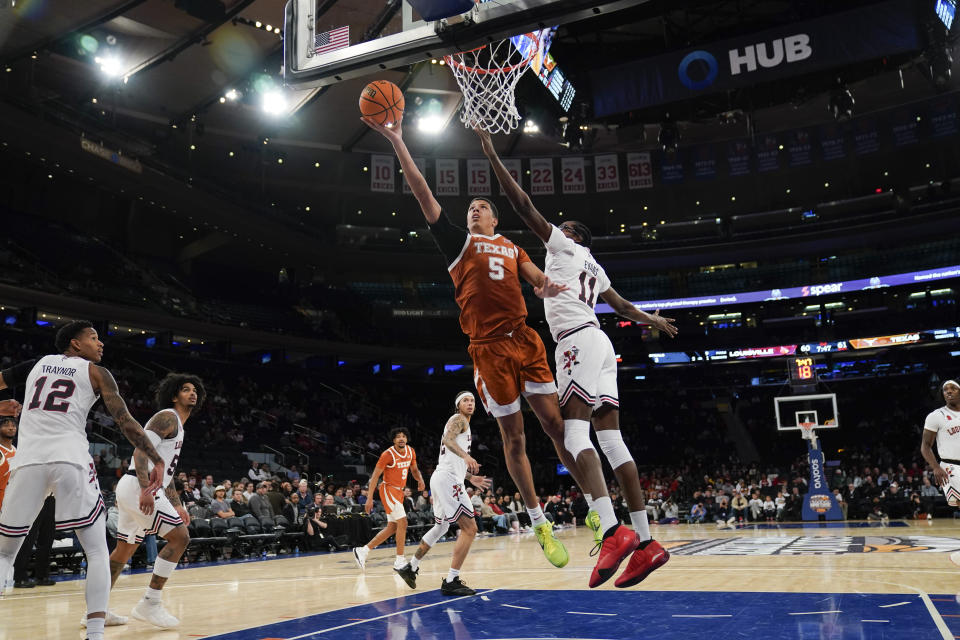 Texas's Kadin Shedrick, left, puts up a shot past Louisville's Dennis Evans during the second half of an NCAA college basketball game, Sunday, Nov. 19, 2023, in New York. (AP Photo/Seth Wenig)