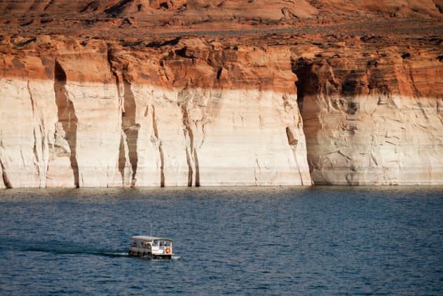 A boat in a lake with a dry cliff behind it.