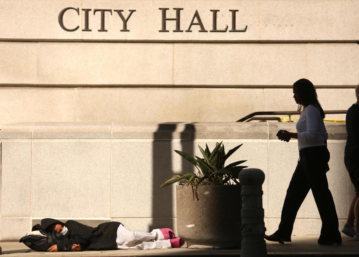A homeless person sleeps on the sidewalk outside Los Angeles City Hall.