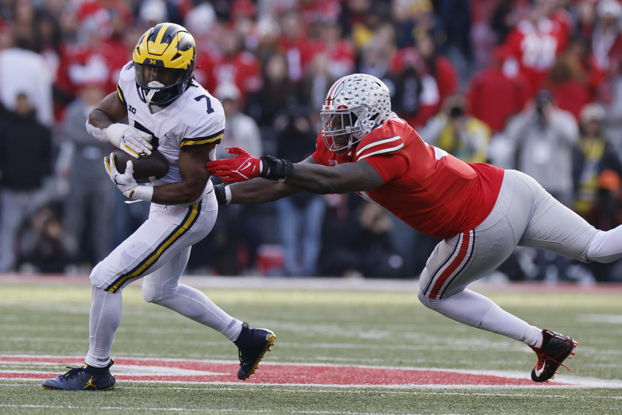Michigan running back Donovan Edwards, left, turns up field past Ohio State defensive lineman Zach Harrison during the second half of an NCAA college football game on Saturday, Nov. 26, 2022, in Columbus, Ohio. (AP Photo/Jay LaPrete)