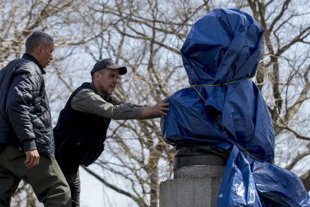 New York City Parks workers work to remove a covered large molded bust of Edward Snowden at Fort Greene Park in Brooklyn, New York April 6, 2015. REUTERS/Brendan McDermid