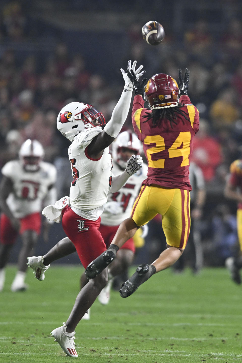 Southern California wide receiver Makai Lemon (24) makes a catch in front of Louisville linebacker Antonio Watts (35) during the first half of the Holiday Bowl NCAA college football game Wednesday, Dec. 27, 2023, in San Diego. (AP Photo/Denis Poroy)