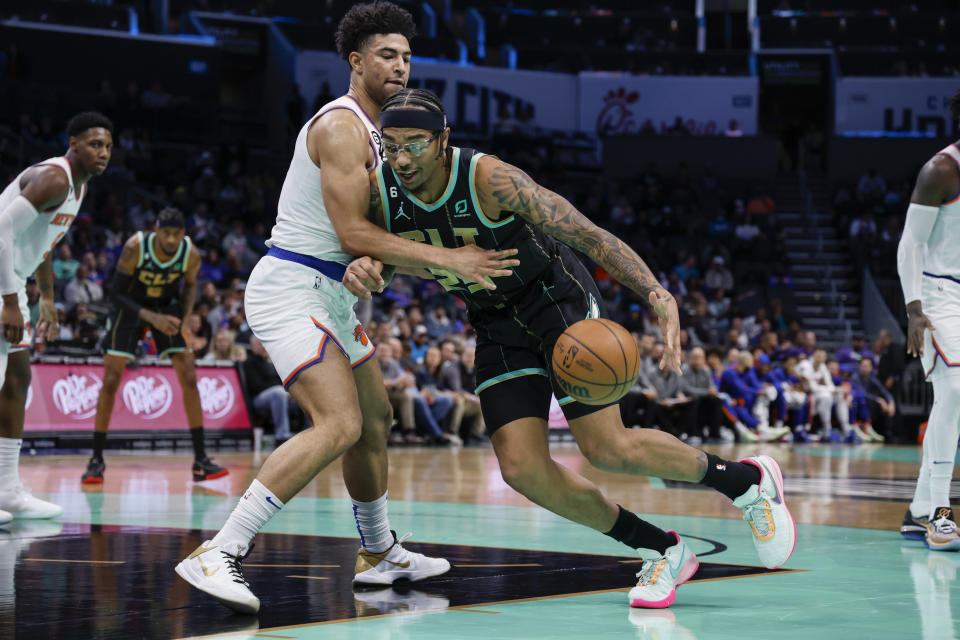 Charlotte Hornets forward P.J. Washington, center right, drives into New York Knicks guard Quentin Grimes, center left, during the first half of an NBA basketball game in Charlotte, N.C., Friday, Dec. 9, 2022. (AP Photo/Nell Redmond)